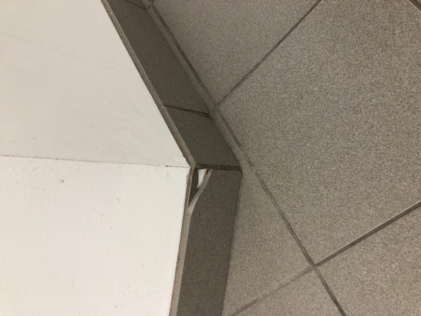 A corner of the floor with a metal strip on it.
