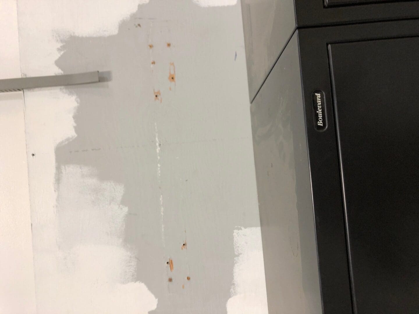A wall with paint peeling off of it and the walls are white.
