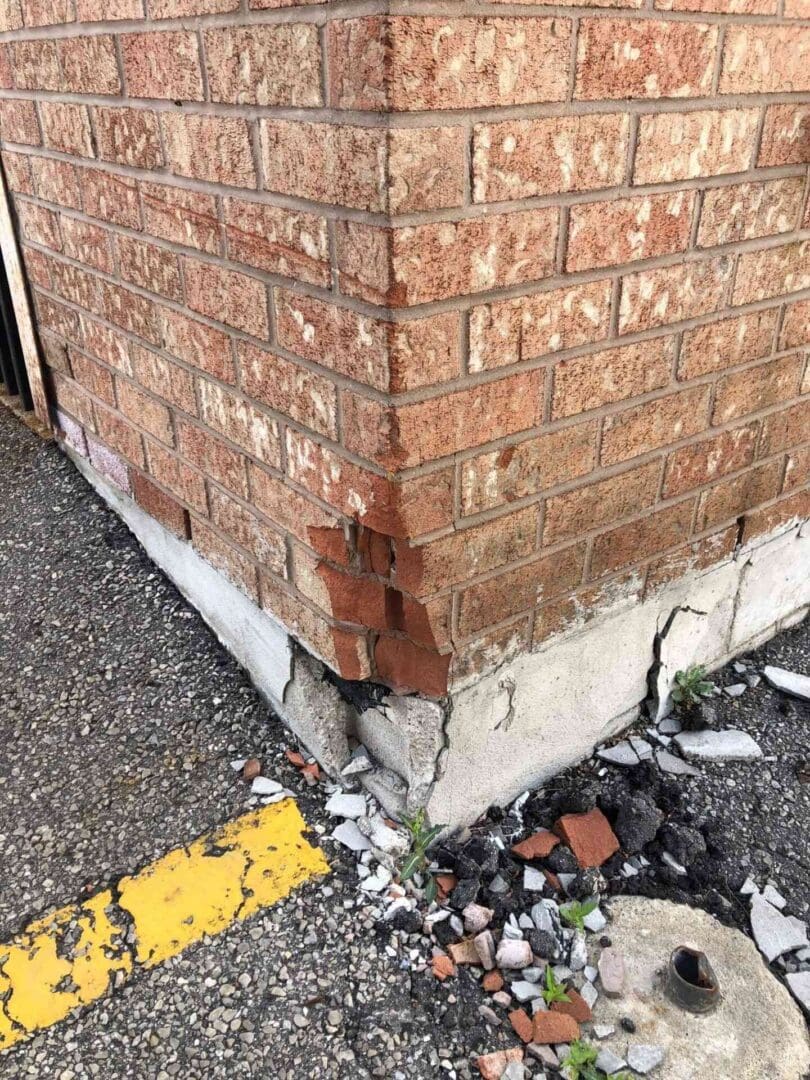 A brick wall with peeling paint and a yellow curb.