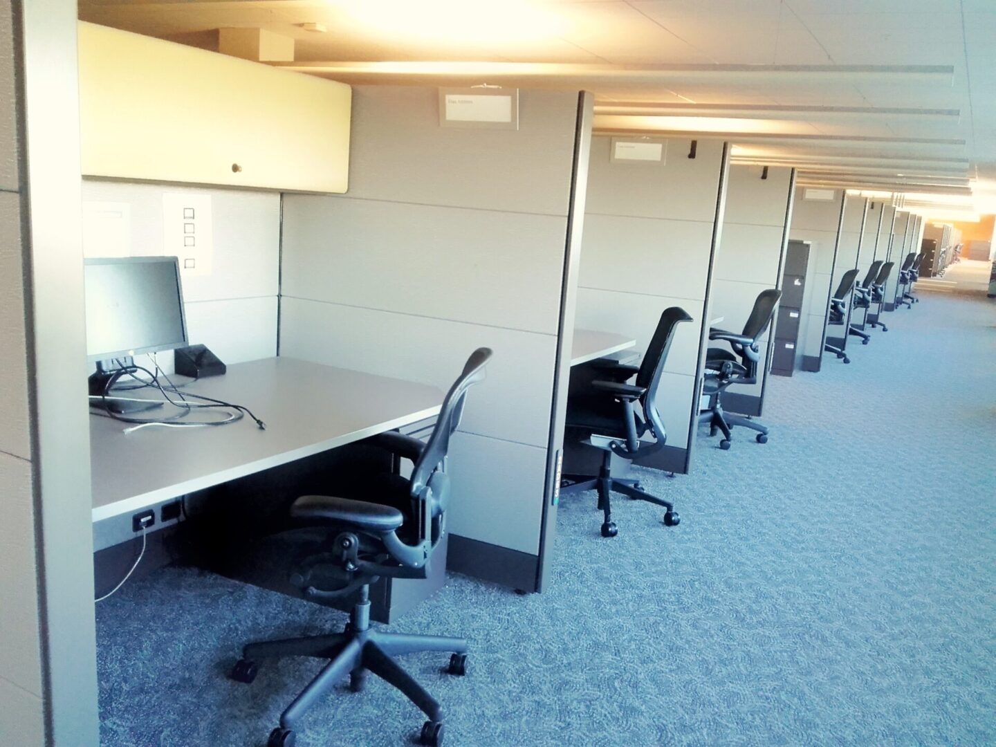 A row of cubicles with chairs and tables in it.