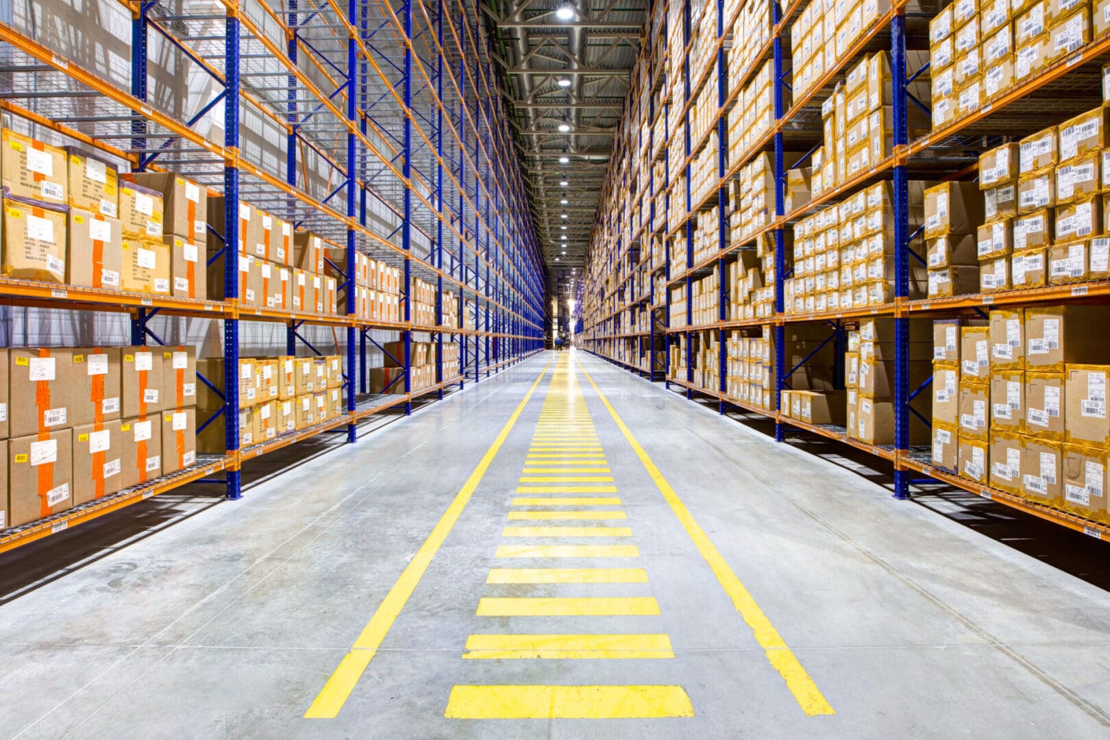 A warehouse with many shelves of boxes and yellow lines.