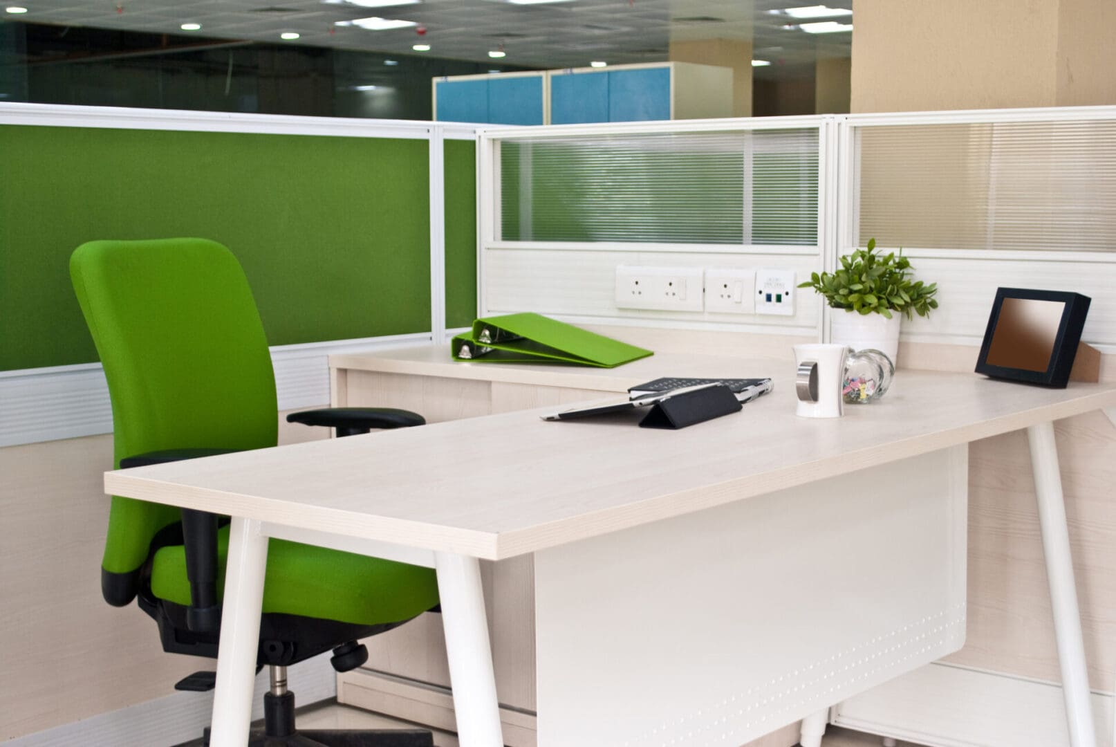 A white desk with green chairs and a window.