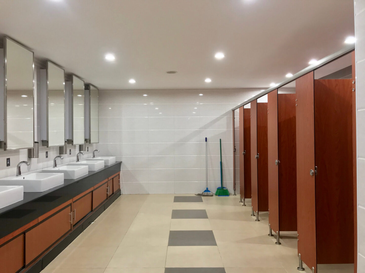 A bathroom with many stalls and sinks
