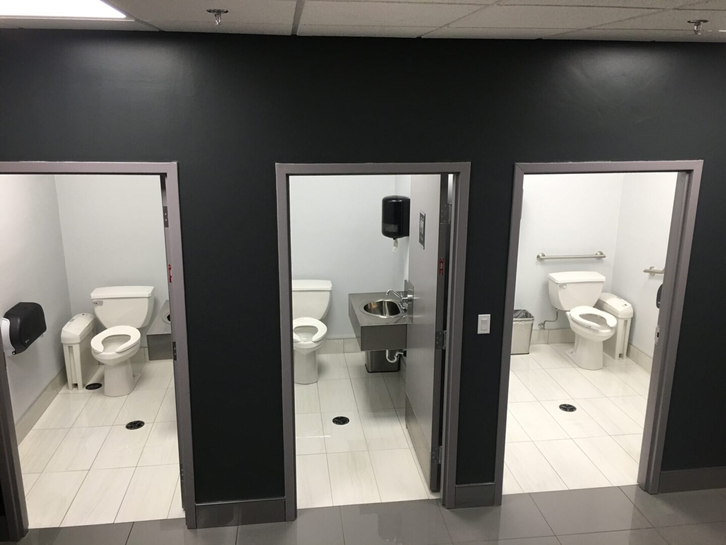 A bathroom with two toilets and three sinks.