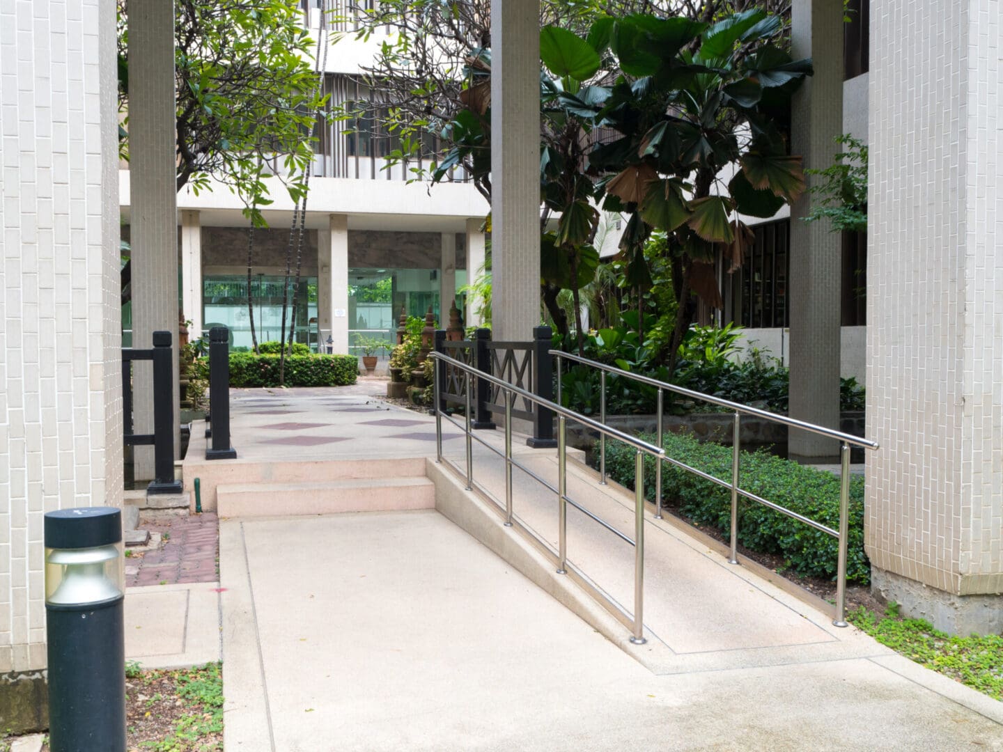 A walkway with metal railing and bushes in the background.