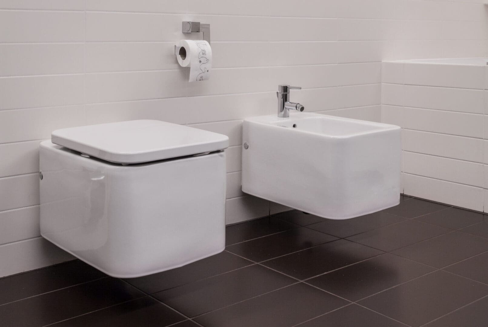 A toilet and sink in a bathroom with black tile.