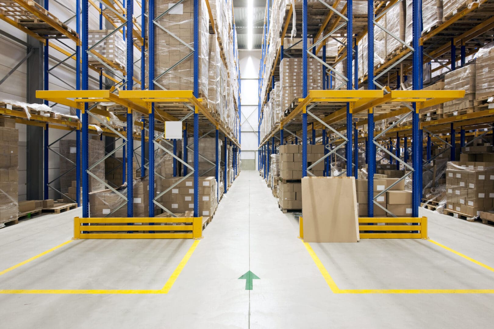 A warehouse with many racks of boxes and a green arrow.