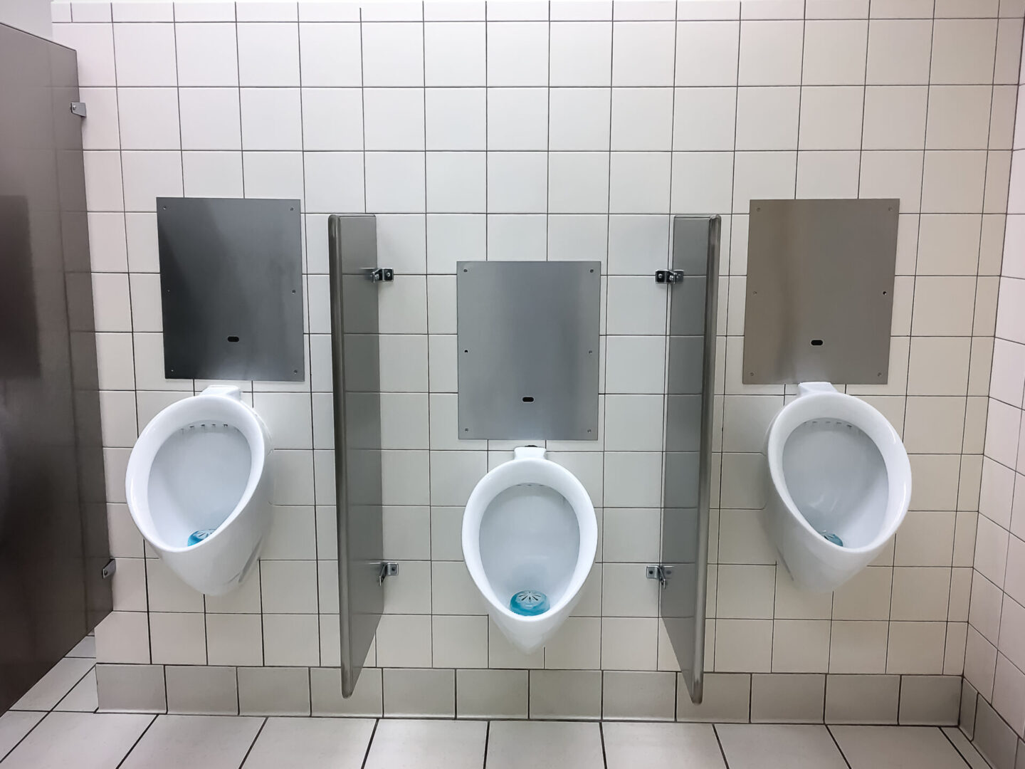 Three urinals are lined up against a wall.