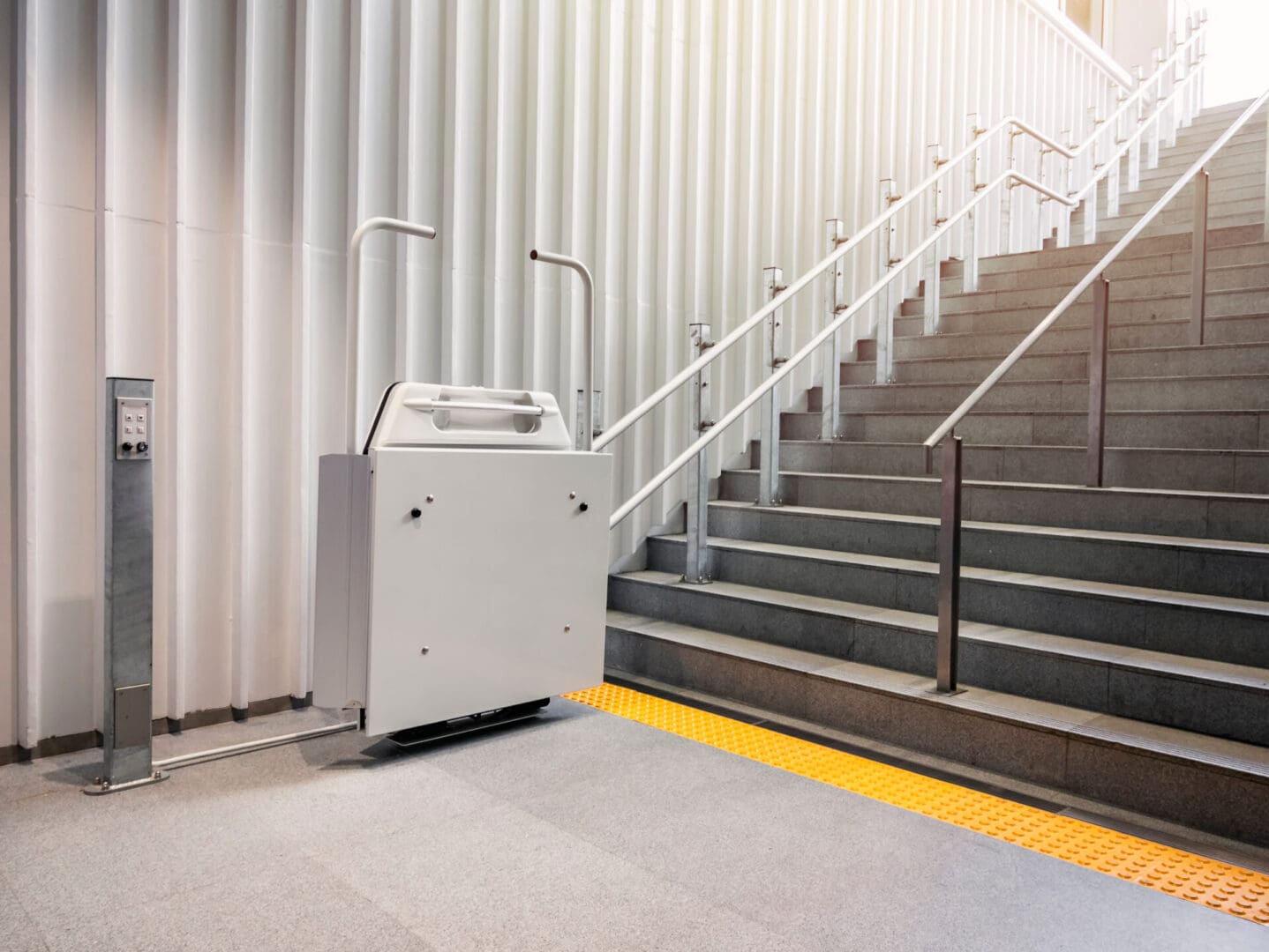 A lift is sitting on the ground near some stairs.