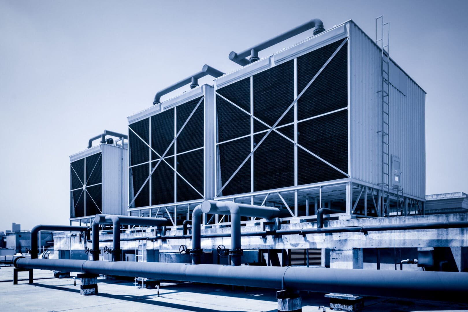 A large cooling tower with pipes in front of it.