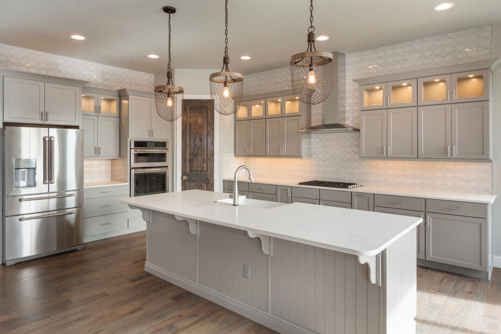 A kitchen with white cabinets and wooden floors.