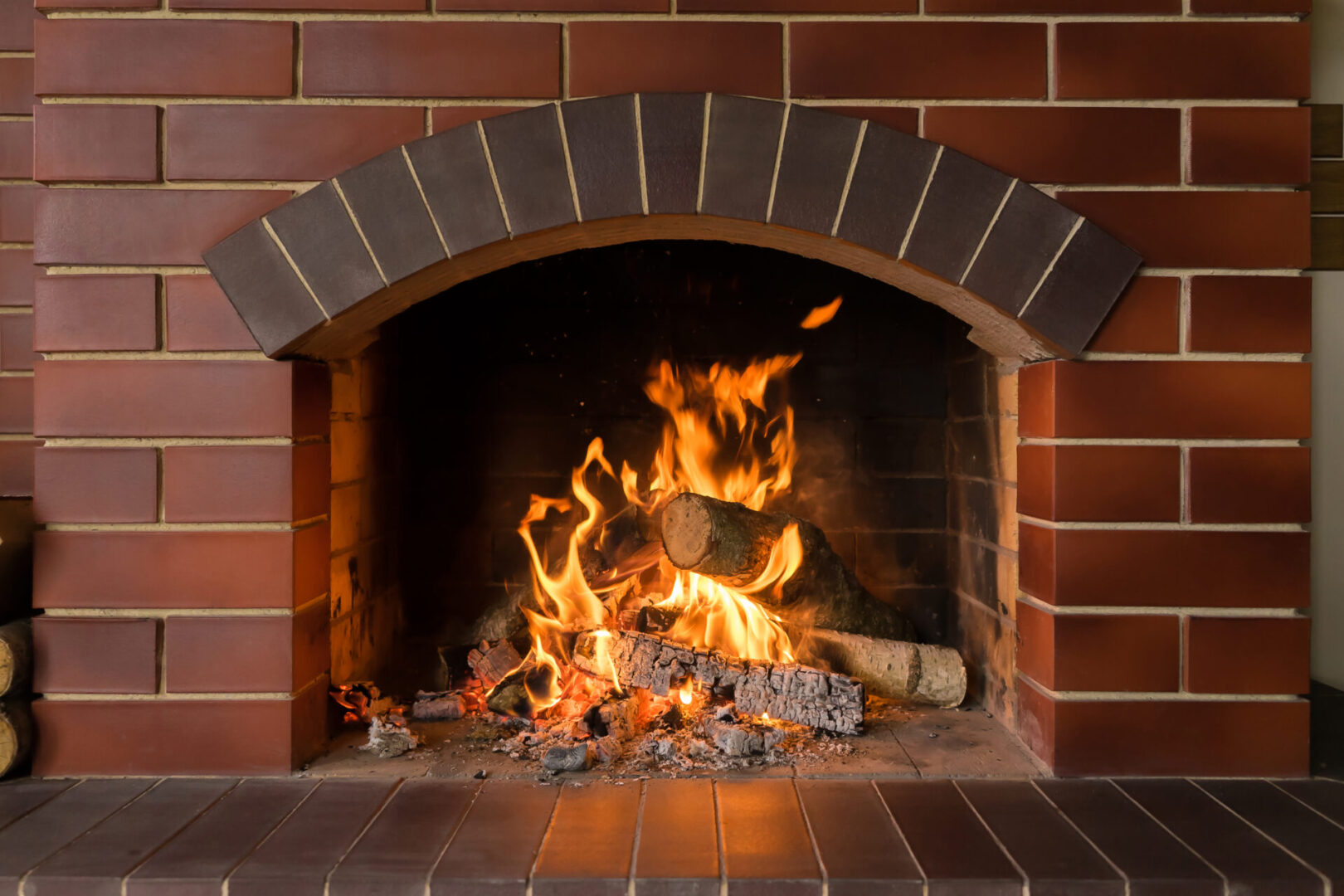 A brick fireplace with fire burning in it.