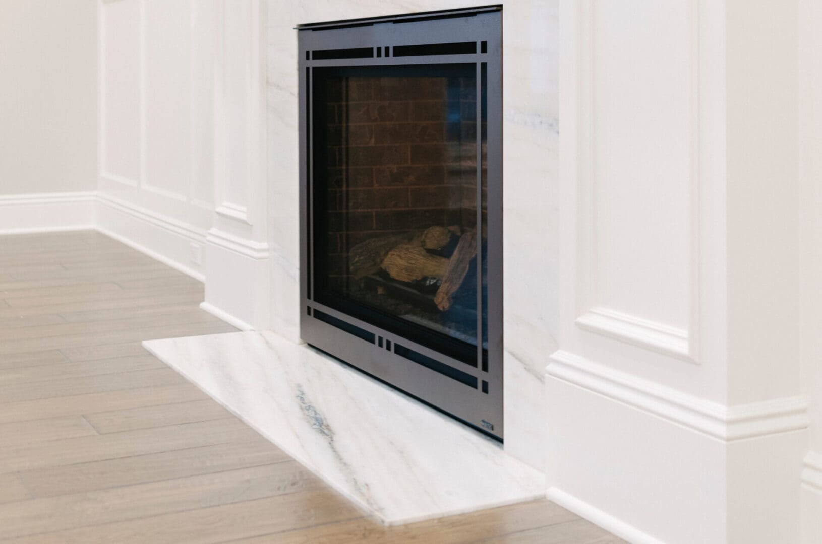 A fireplace with marble surround and white walls.