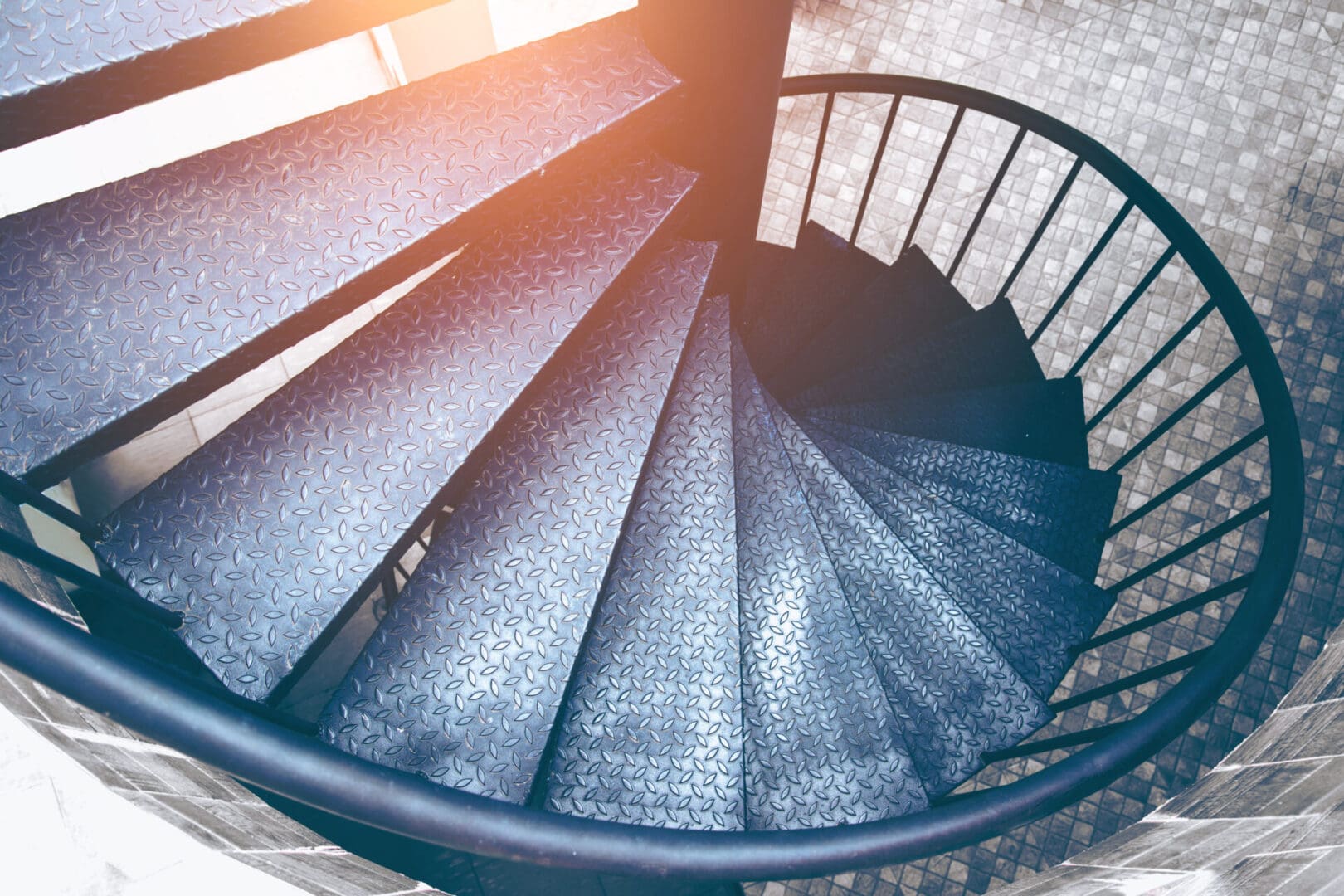 A spiral staircase with blue treads and black railings.