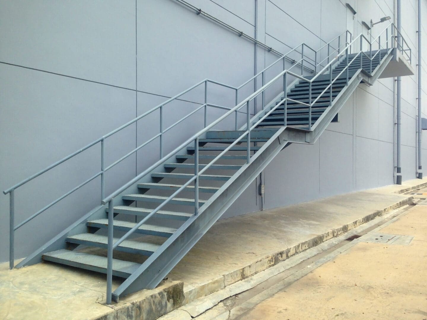 A metal staircase with railing on the side of a building.