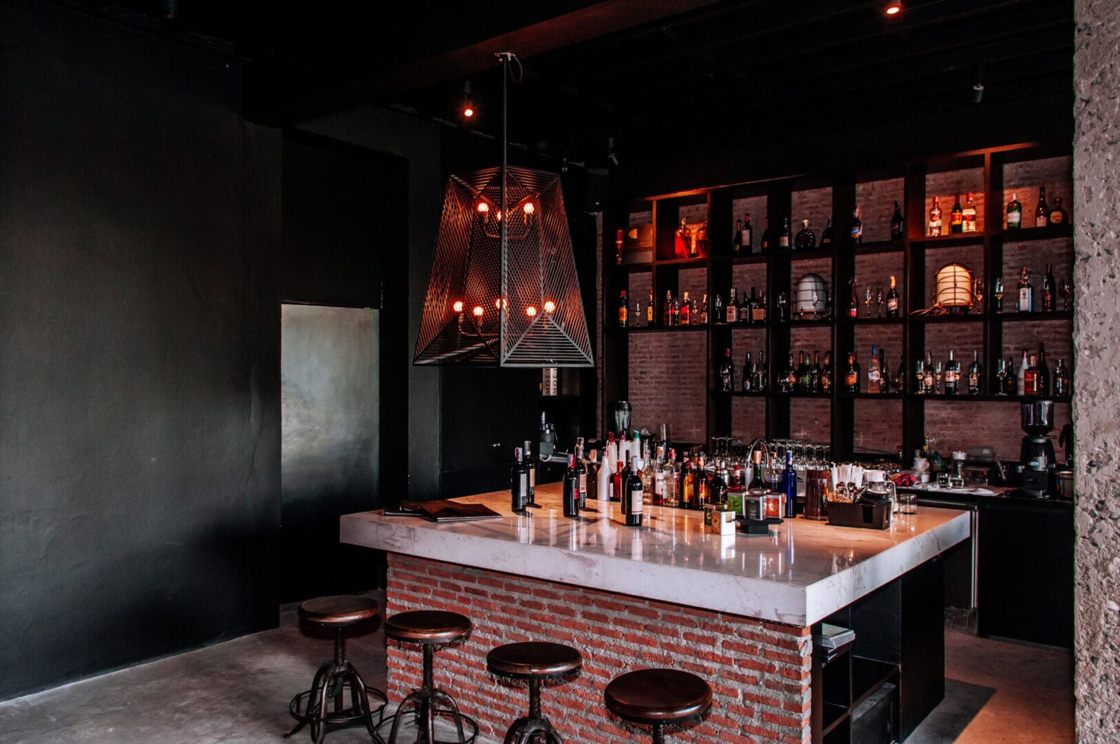 A bar with several stools and bottles of alcohol.