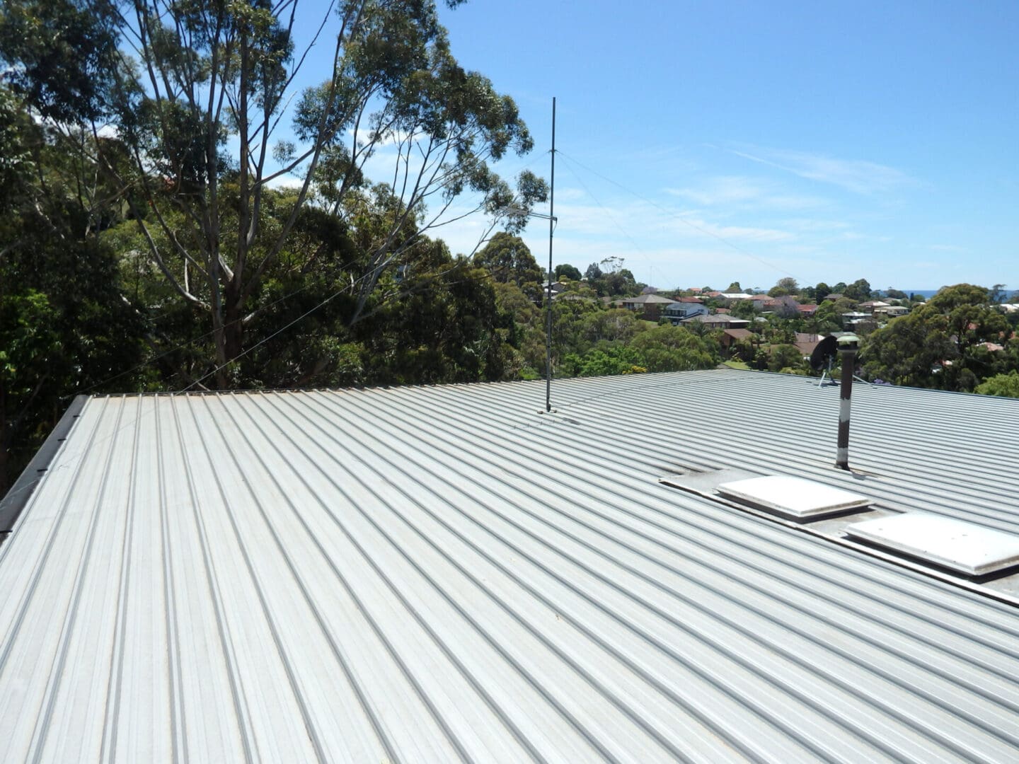 A roof with a metal surface and trees in the background.