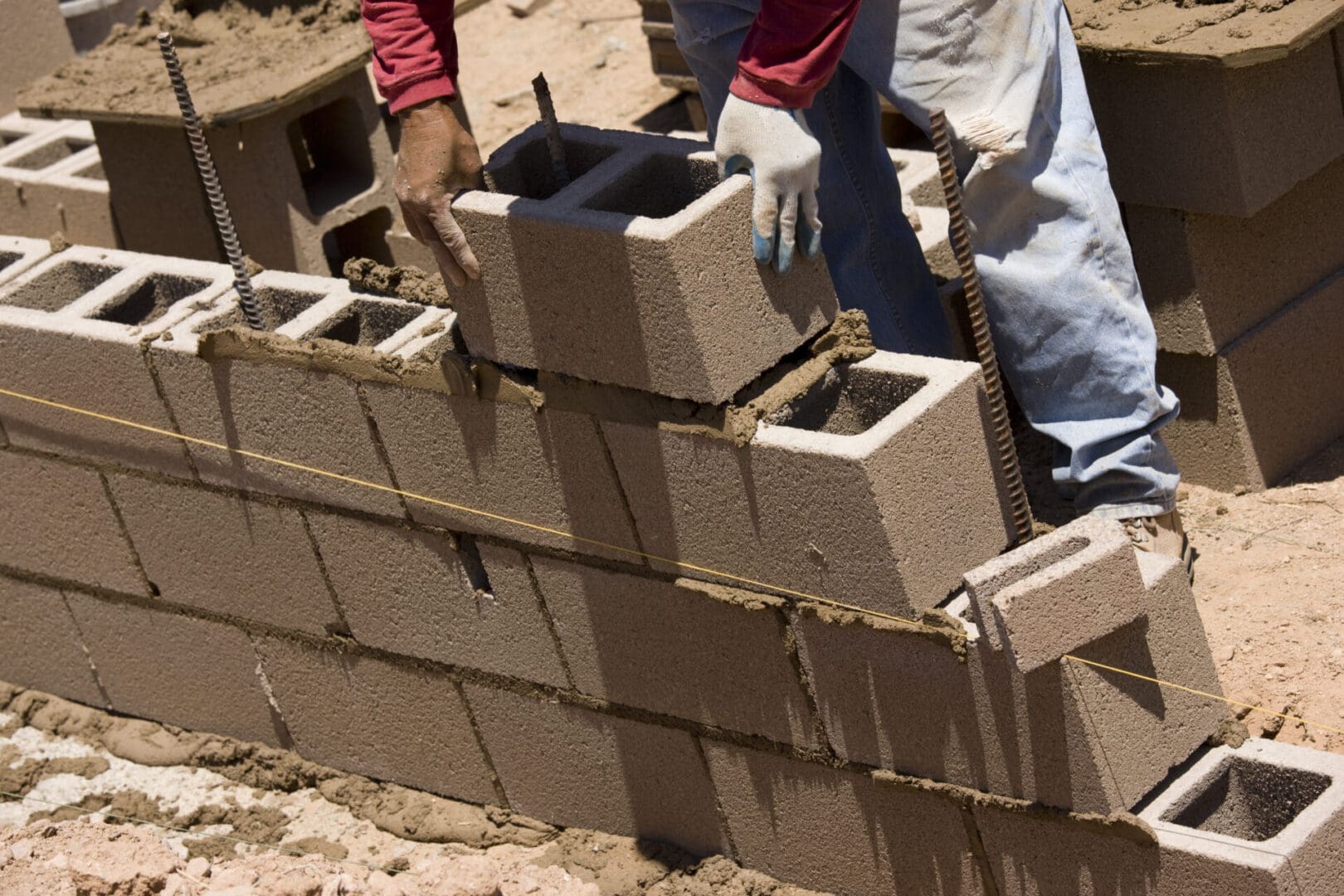 A man building a brick wall with cement blocks.
