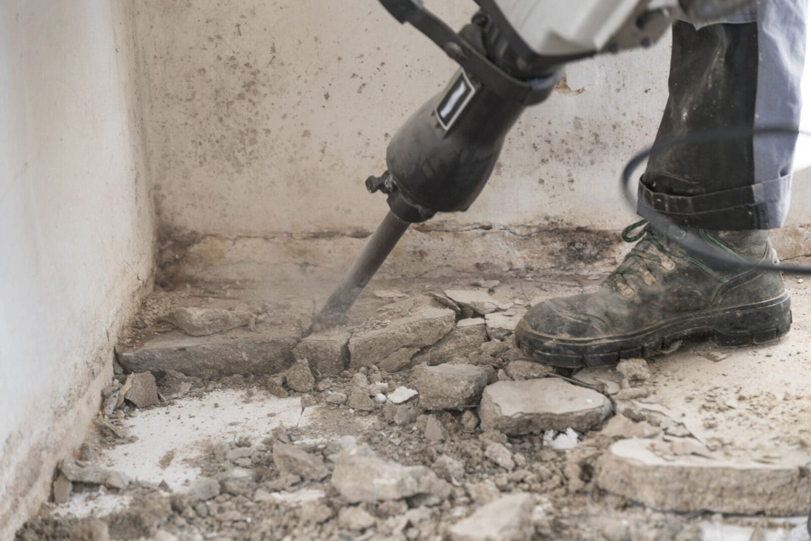 A person using an electric hammer to break up concrete.