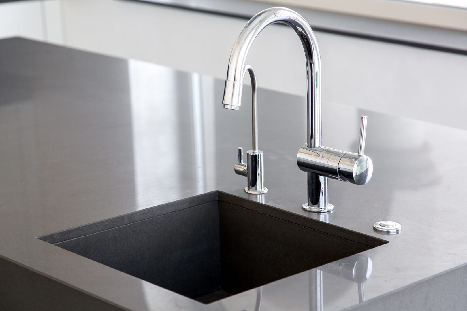 A black sink with chrome faucet and counter.