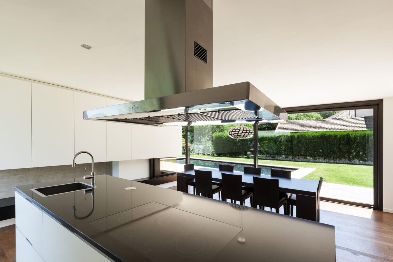 A kitchen with a large window and black counter tops.