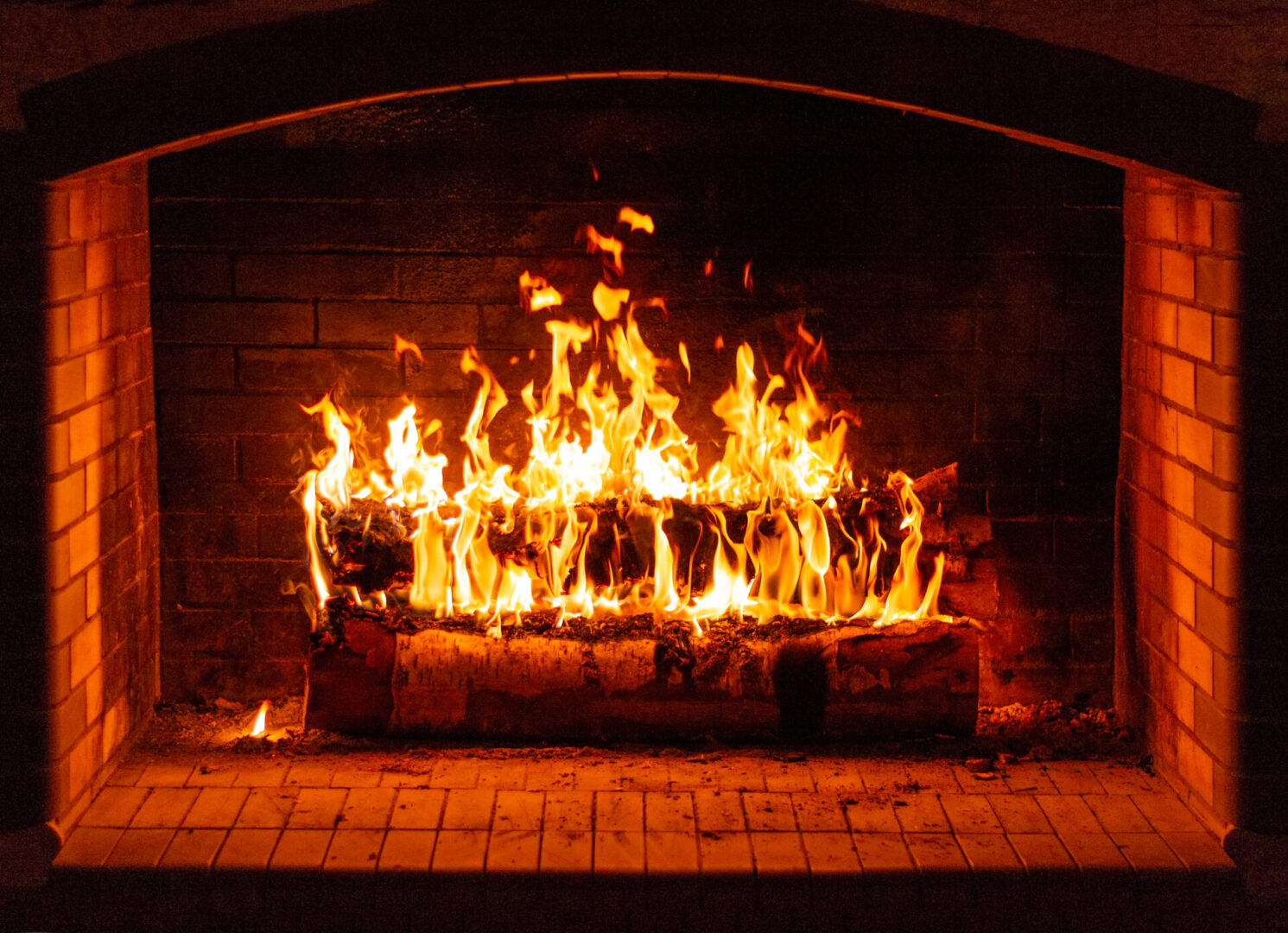 A fire burning in the fireplace with red and yellow flames.