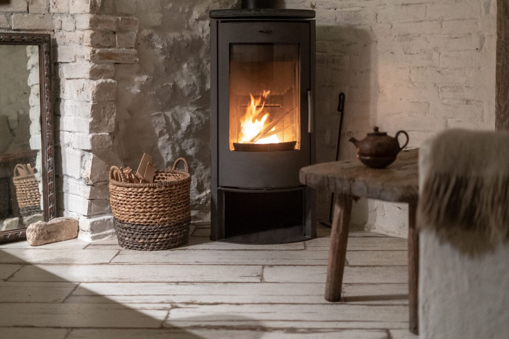 A fireplace in the corner of a room with a table and teapot.