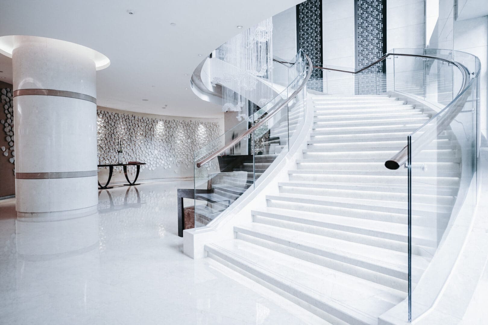 A white staircase with glass railings in the middle of it.