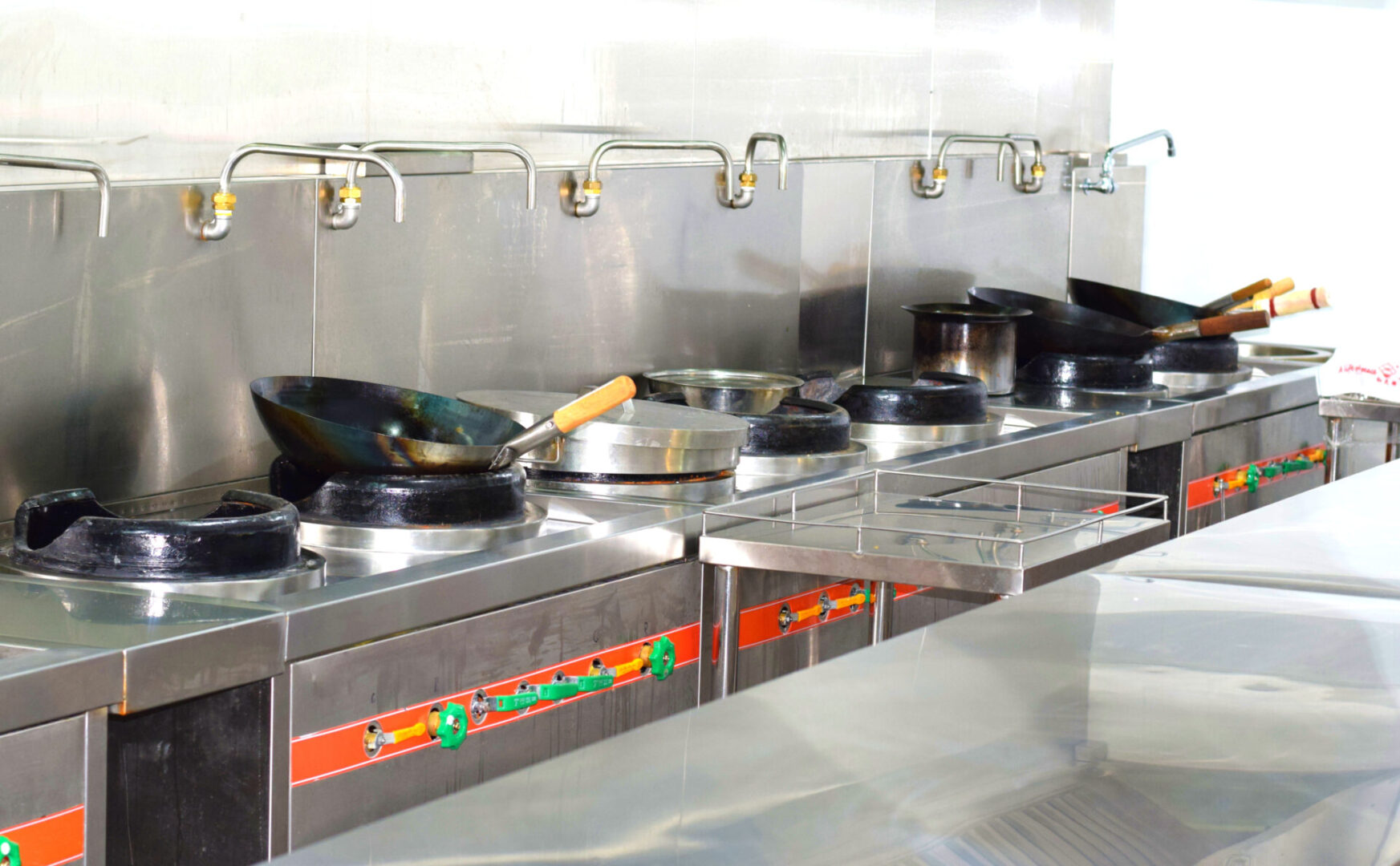 A row of pots and pans in an industrial kitchen.
