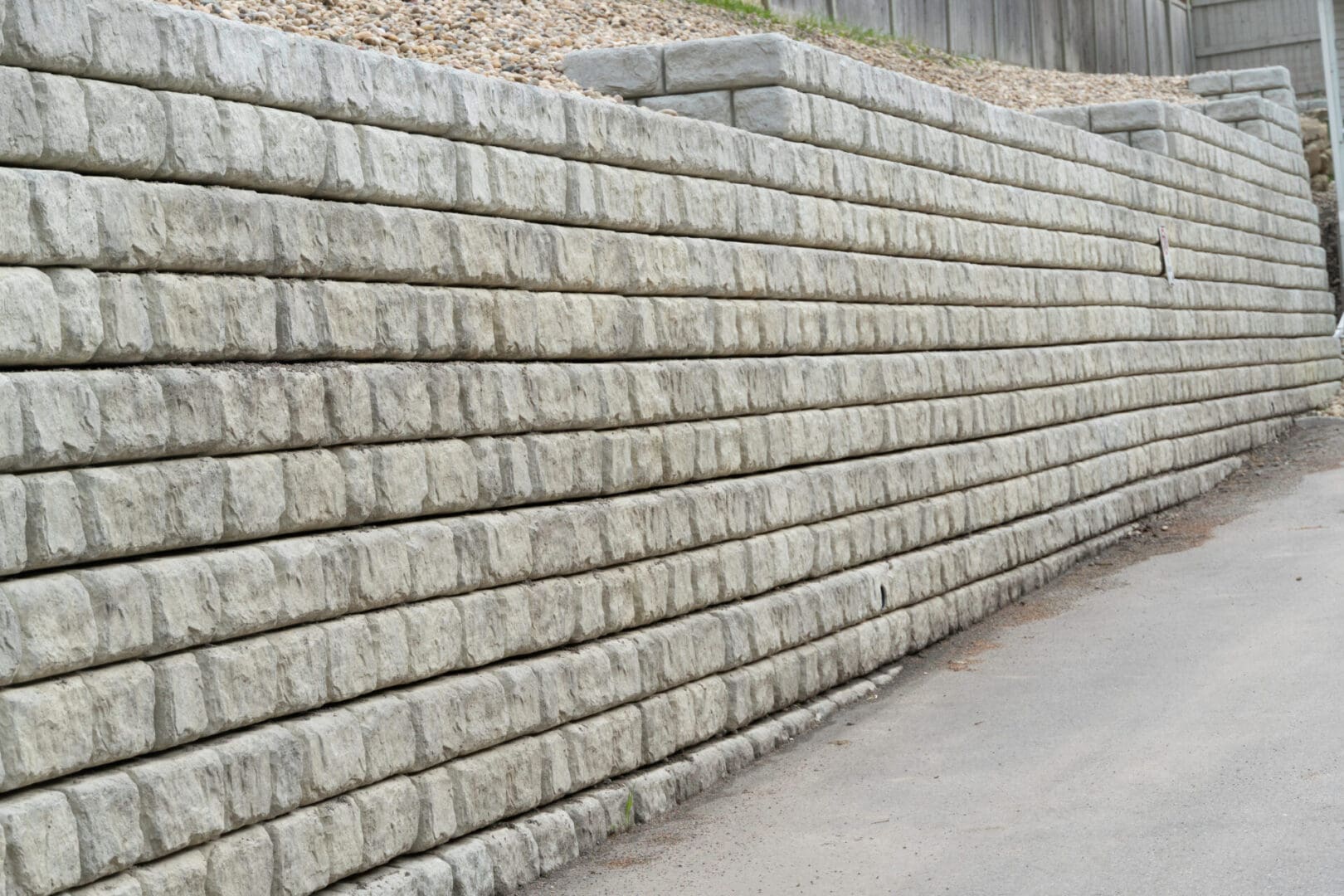 A stone wall with a sidewalk in the background.