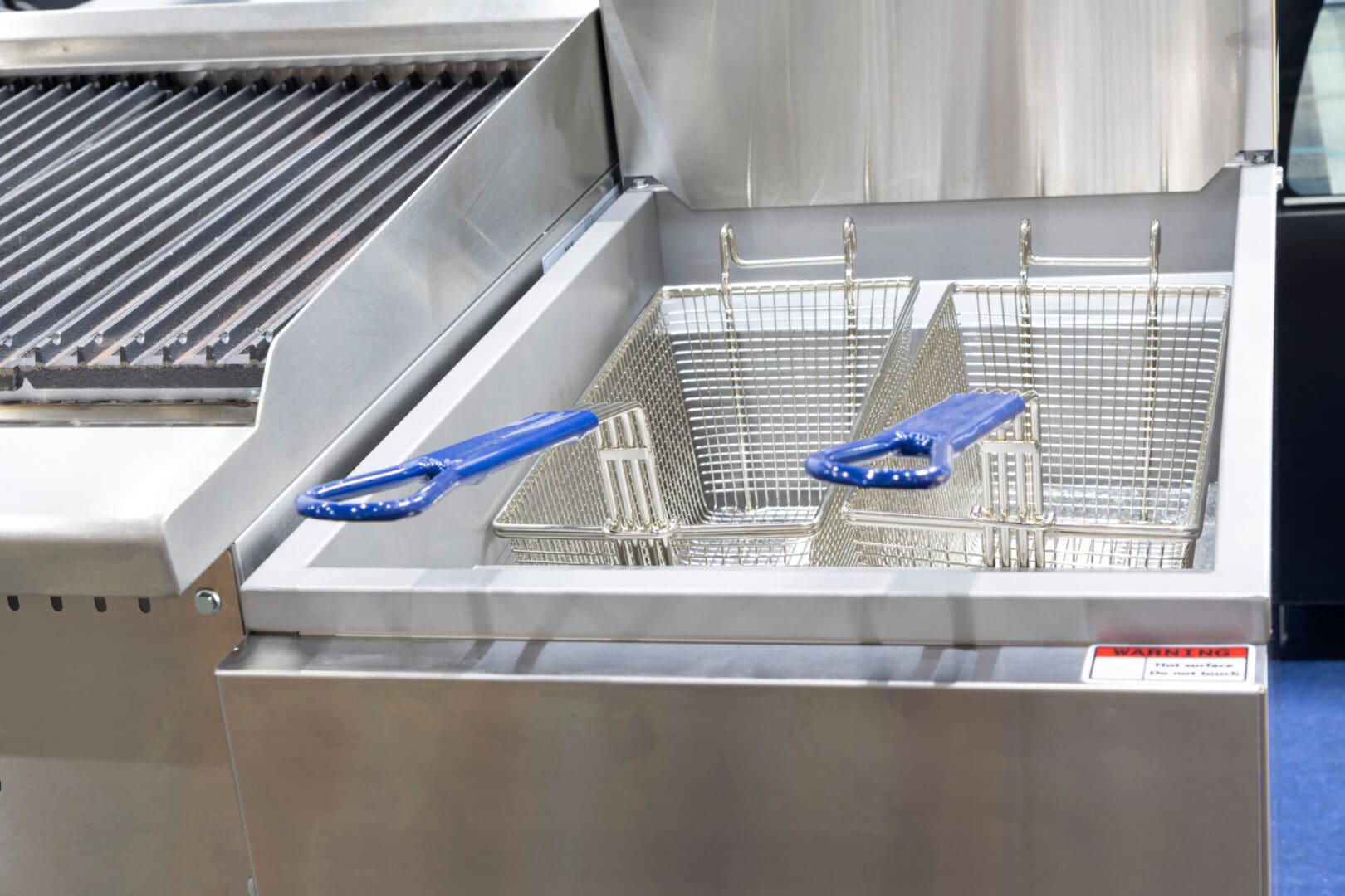 A grill with blue handles and two baskets.