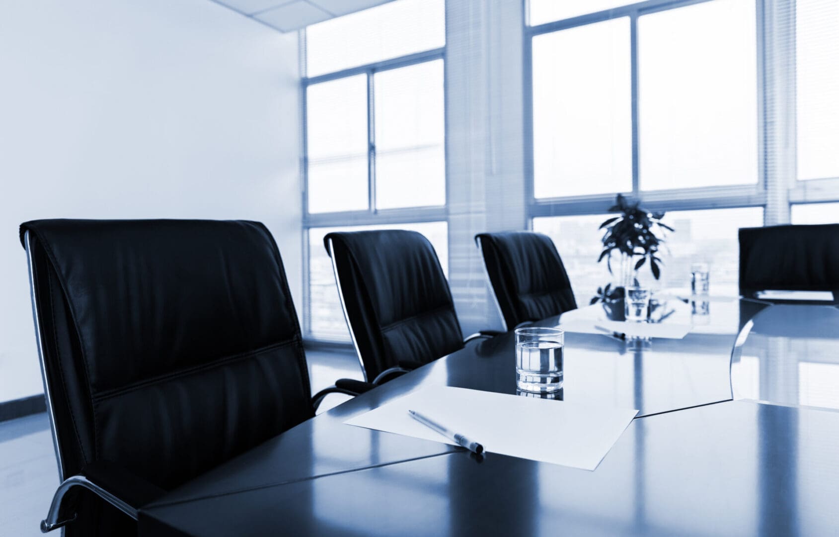 A conference room with chairs and tables in front of windows.