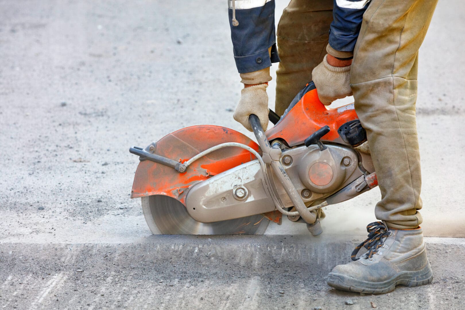 A person cutting concrete with an electric saw.