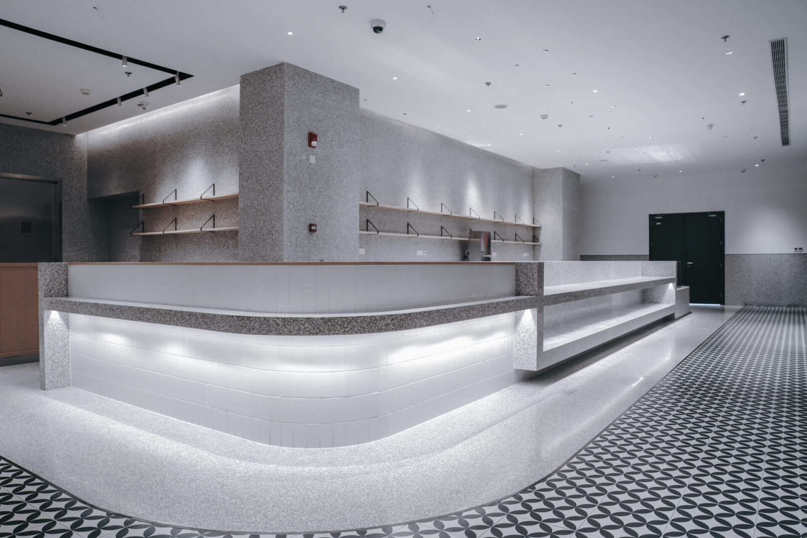 A large white lobby with many counters and lights.