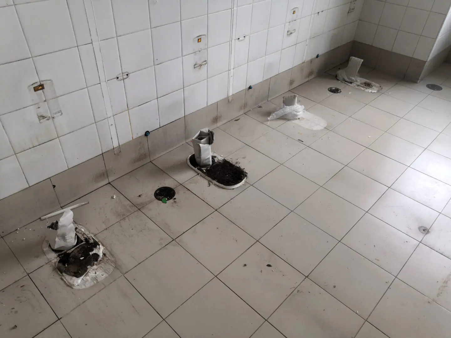 A bathroom with white tile and black floor.