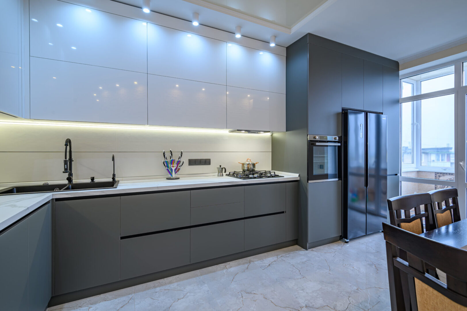 A kitchen with grey cabinets and white walls.