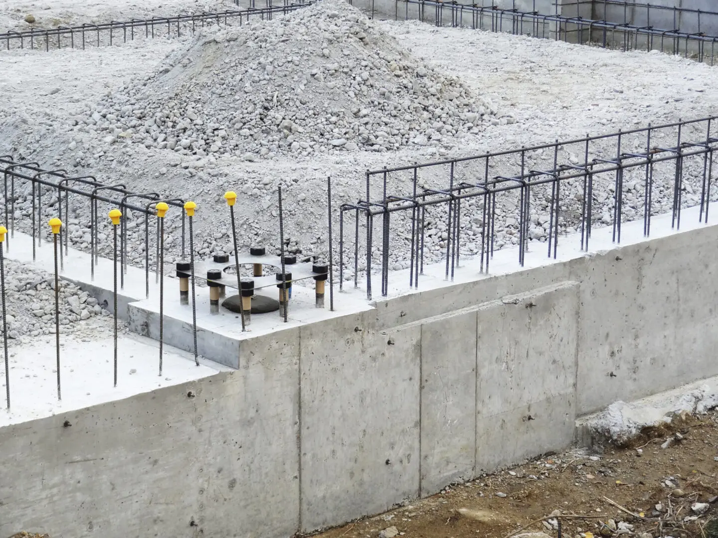 A concrete wall with metal bars and yellow posts.