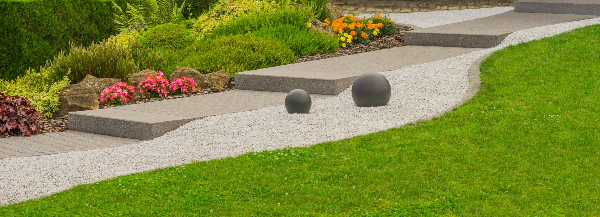 Two balls are on the ground in a garden.