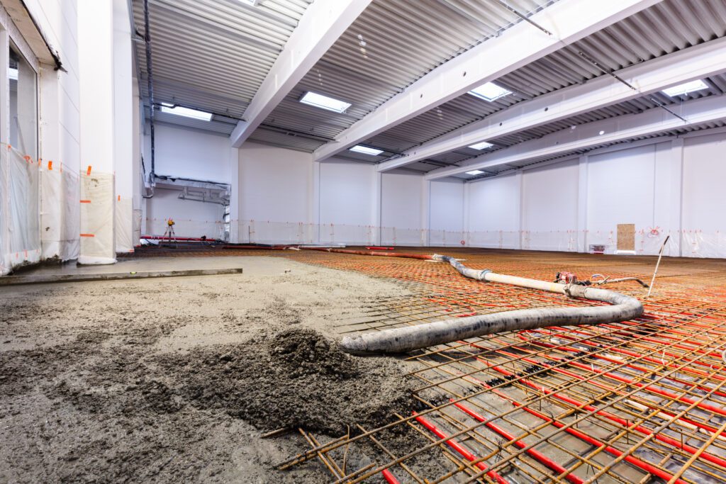 A large room with concrete and pipes in it