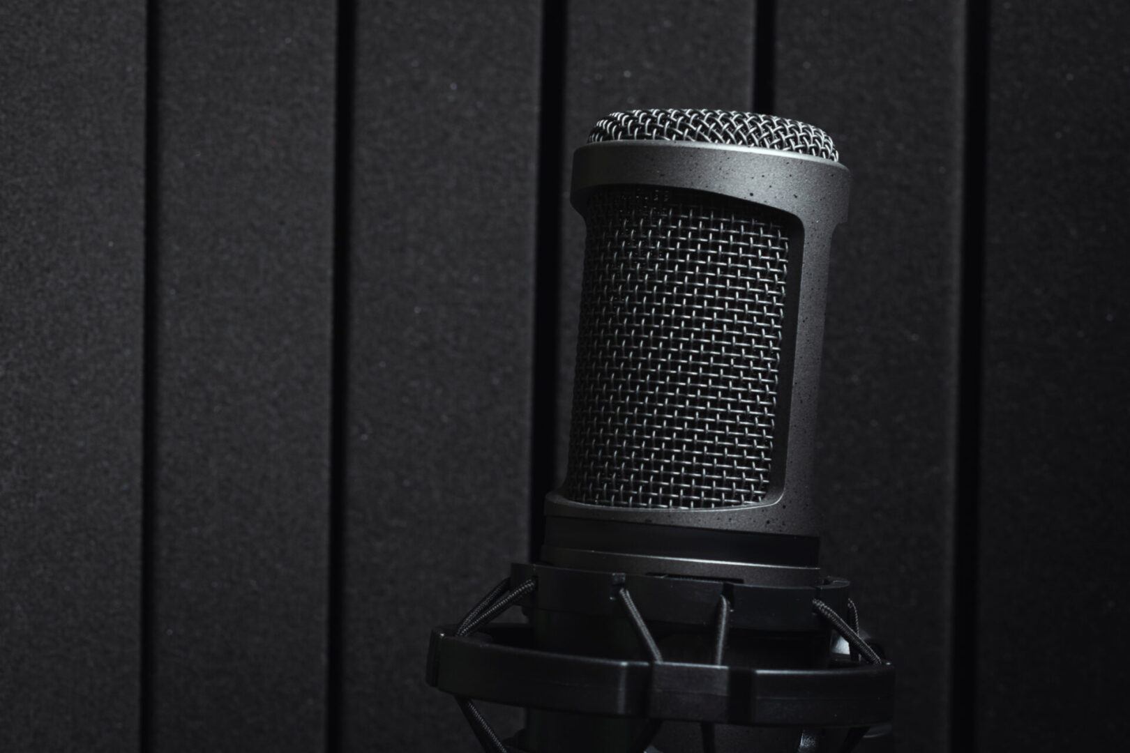 A microphone is sitting in front of a black wall.