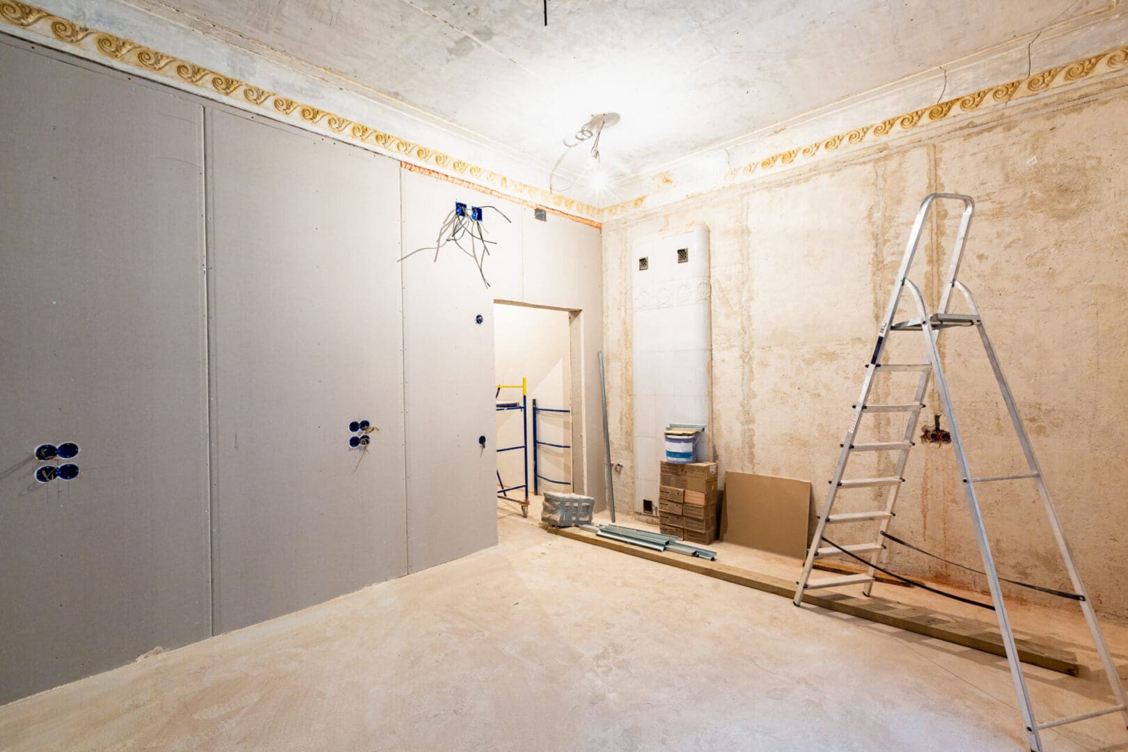 A room with walls being remodeled and a ladder in the middle.