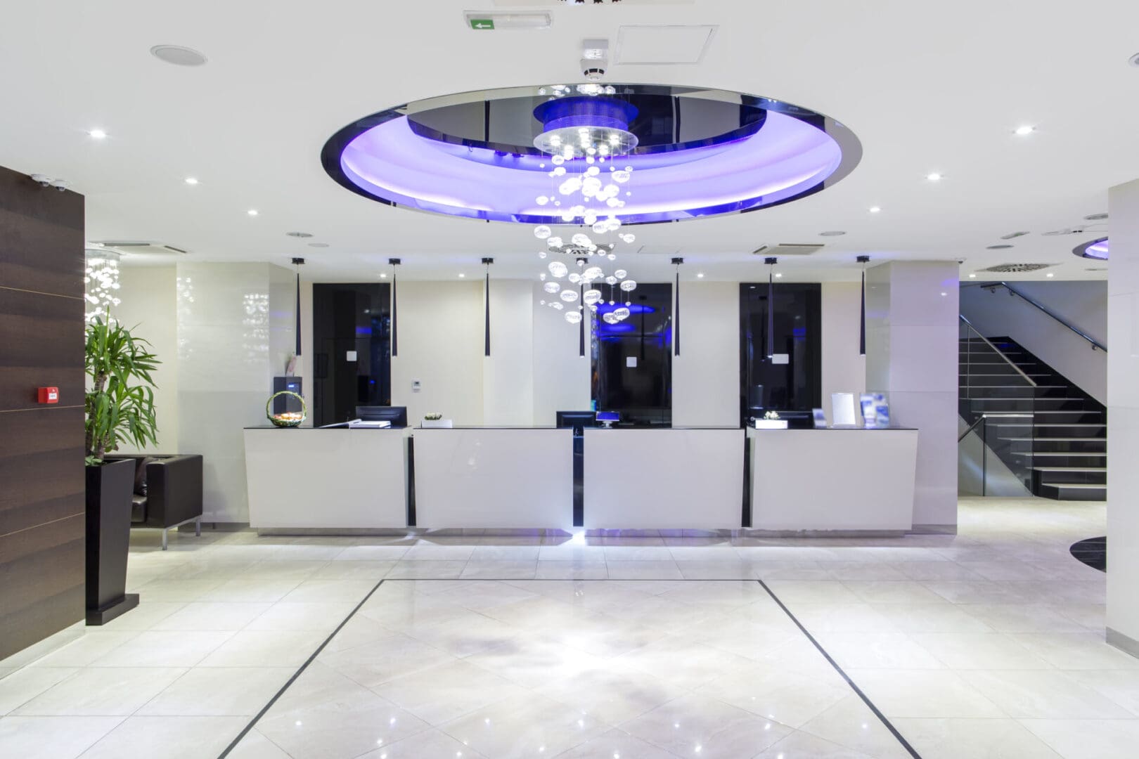 A lobby with a large white counter and blue lights.