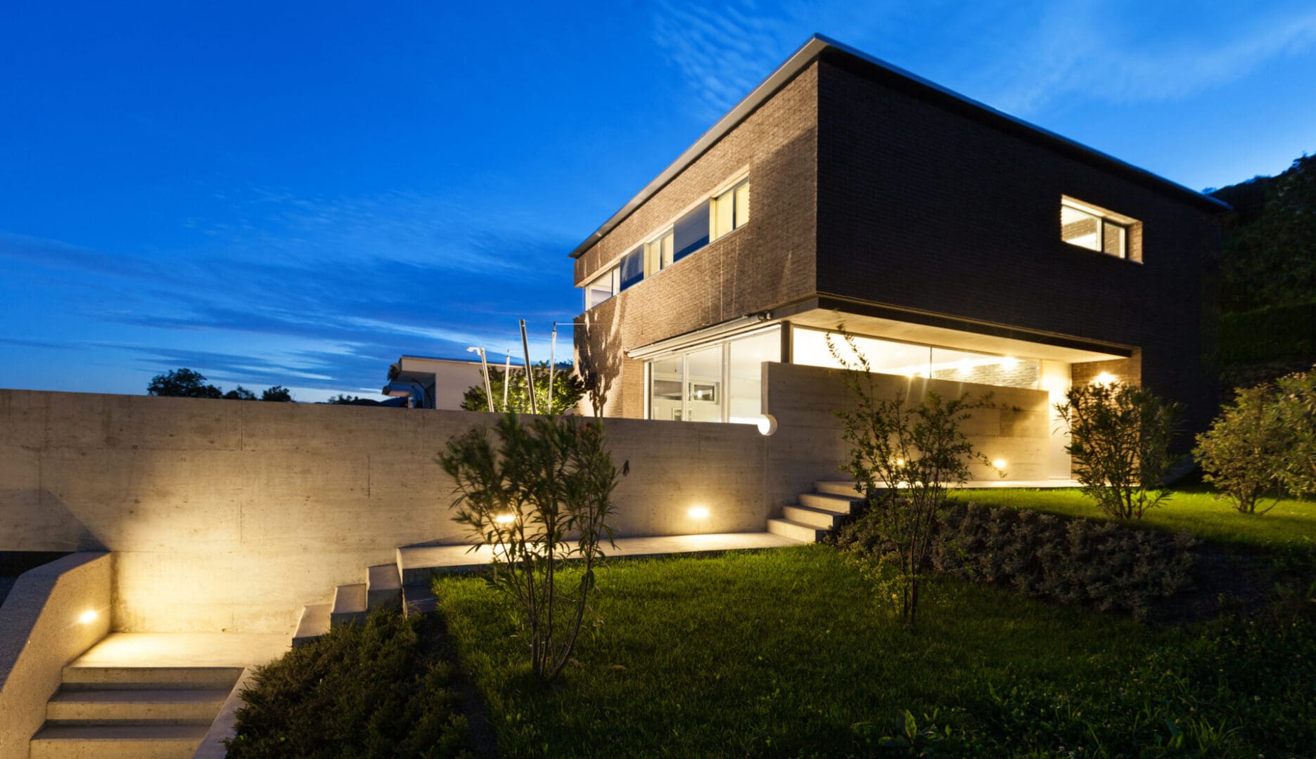 A modern house with lights on the outside of it.