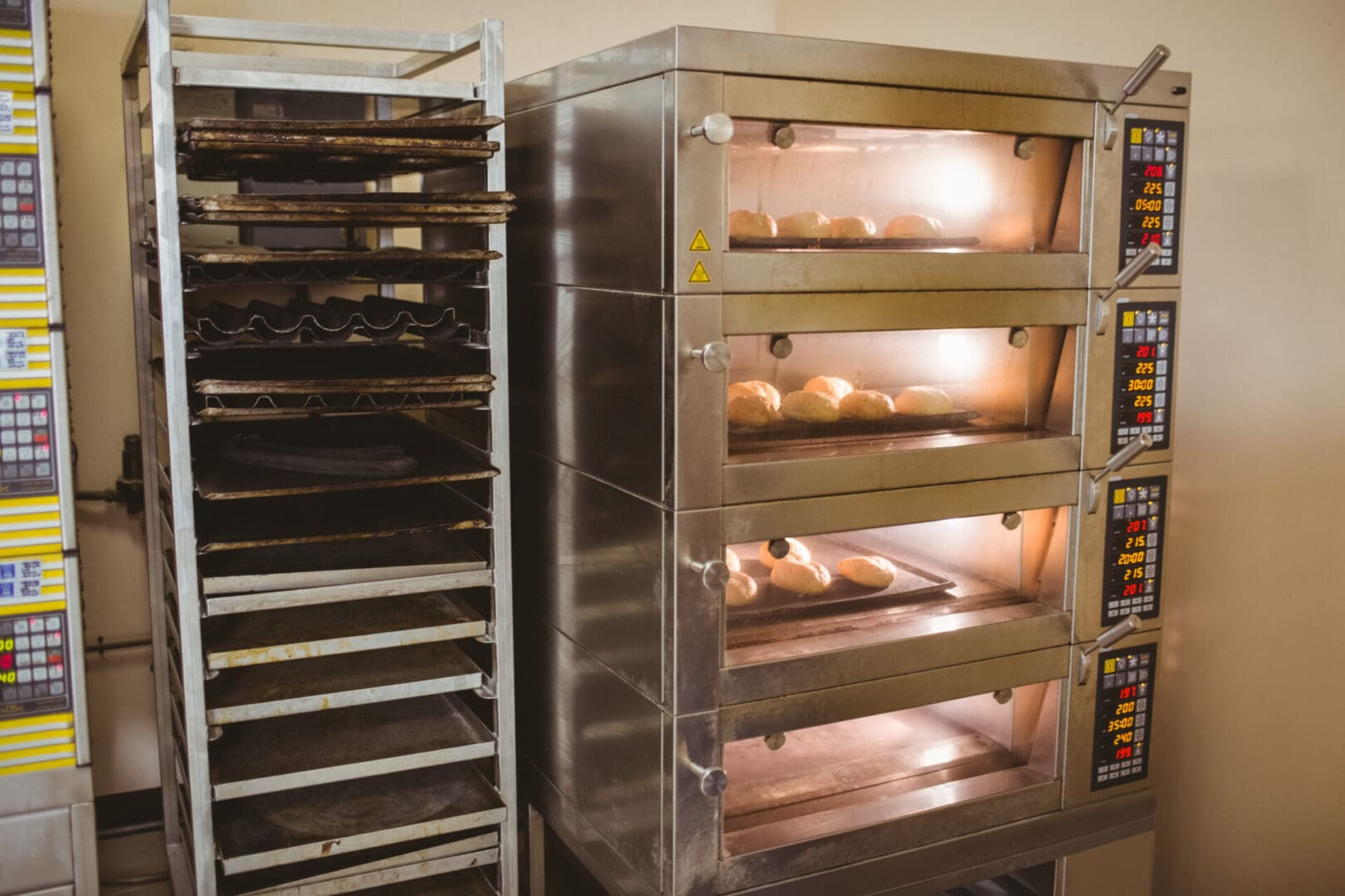 A bakery with four trays of bread in front of the rack.