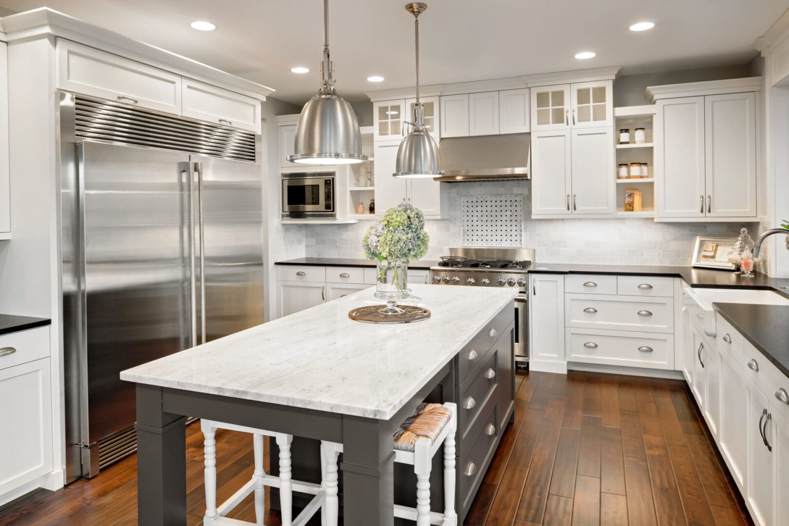 A kitchen with white cabinets and wooden floors.