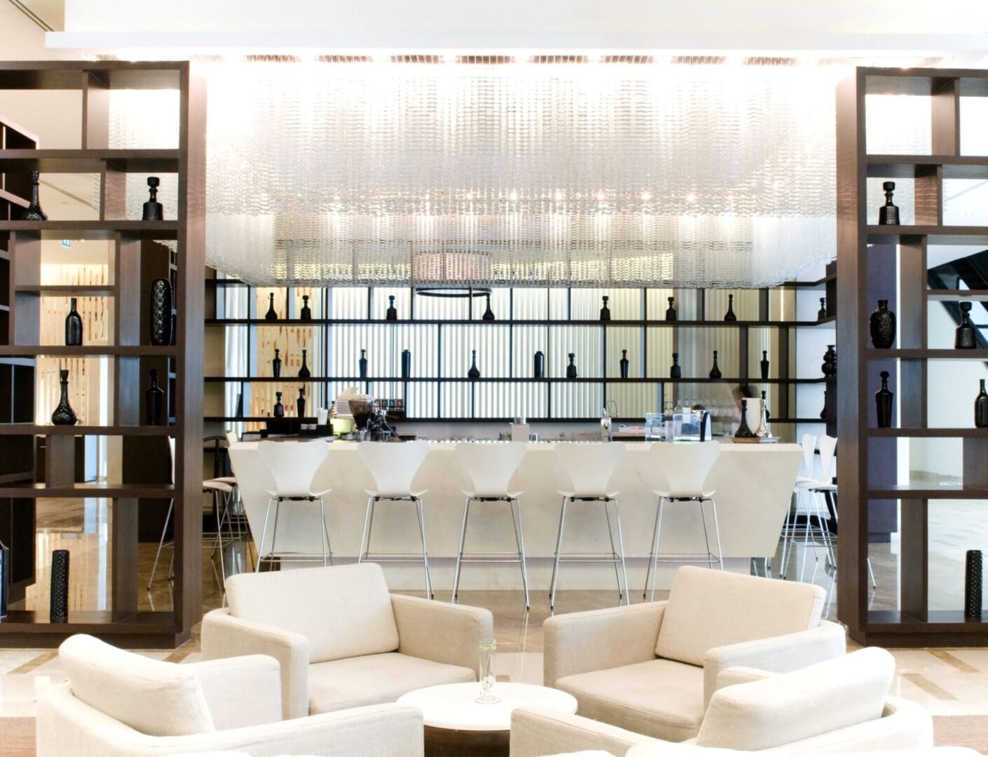 A bar with white chairs and tables in front of it.