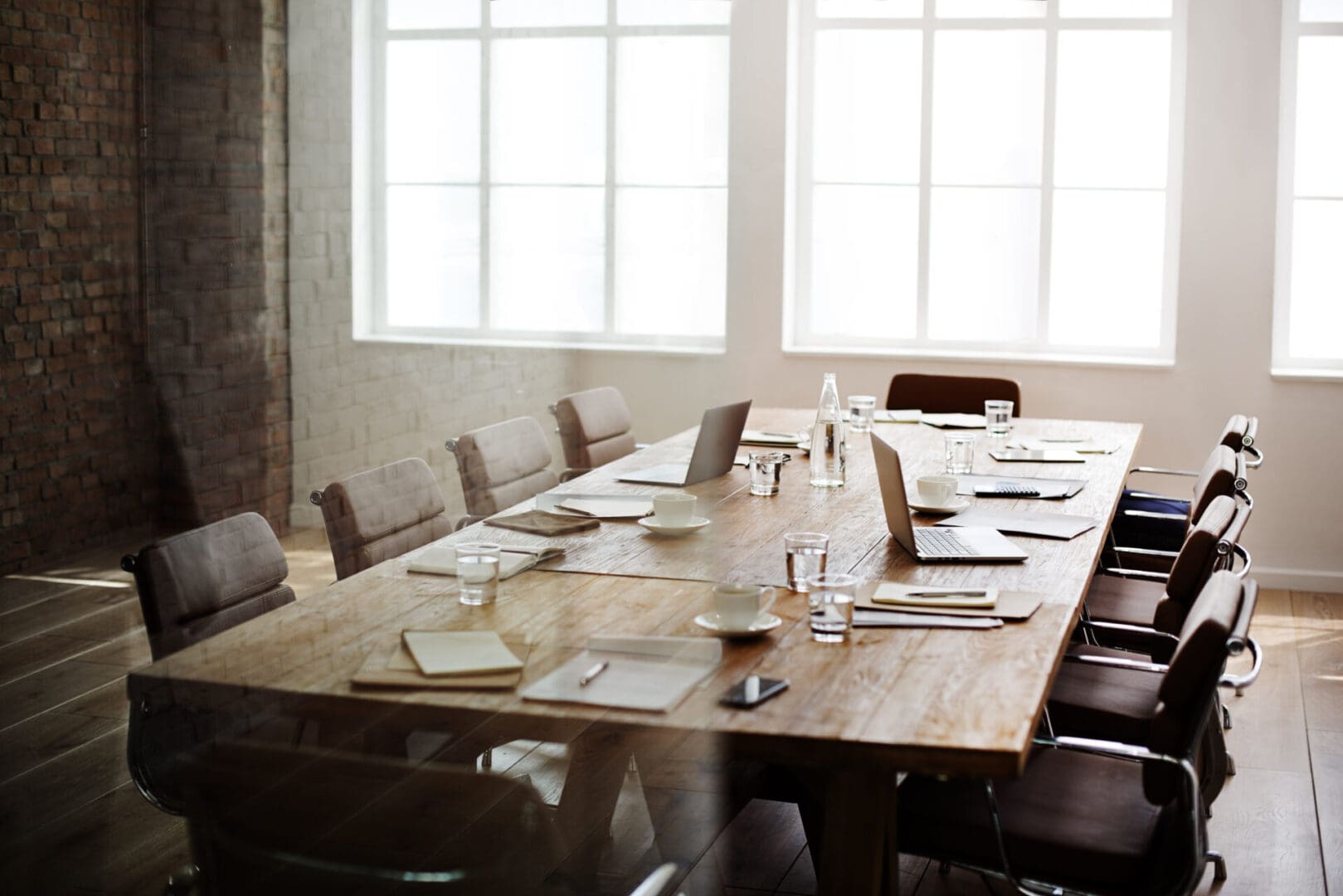 A long wooden table with many empty chairs around it.