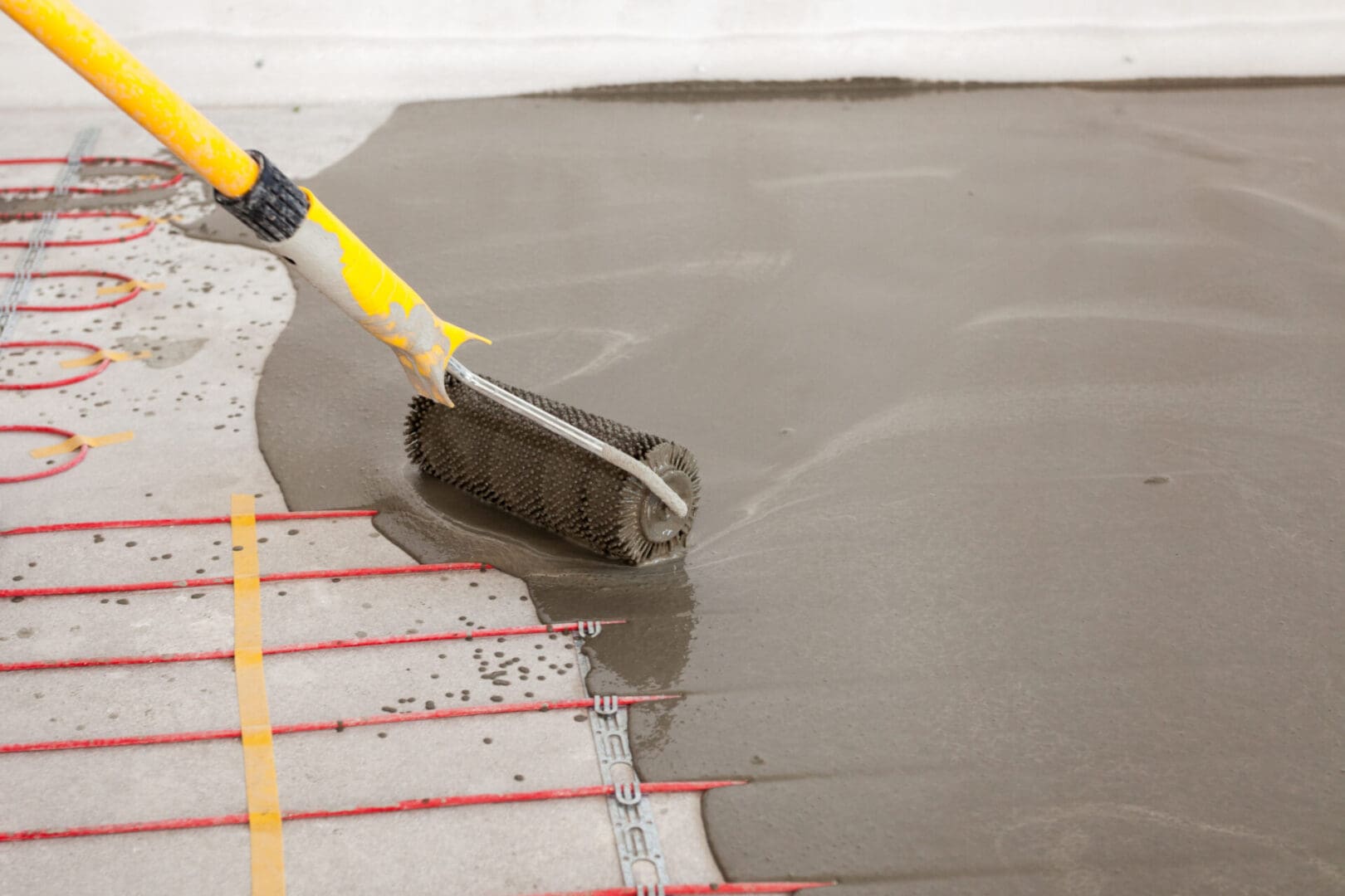 A person is using a roller to smooth the floor.