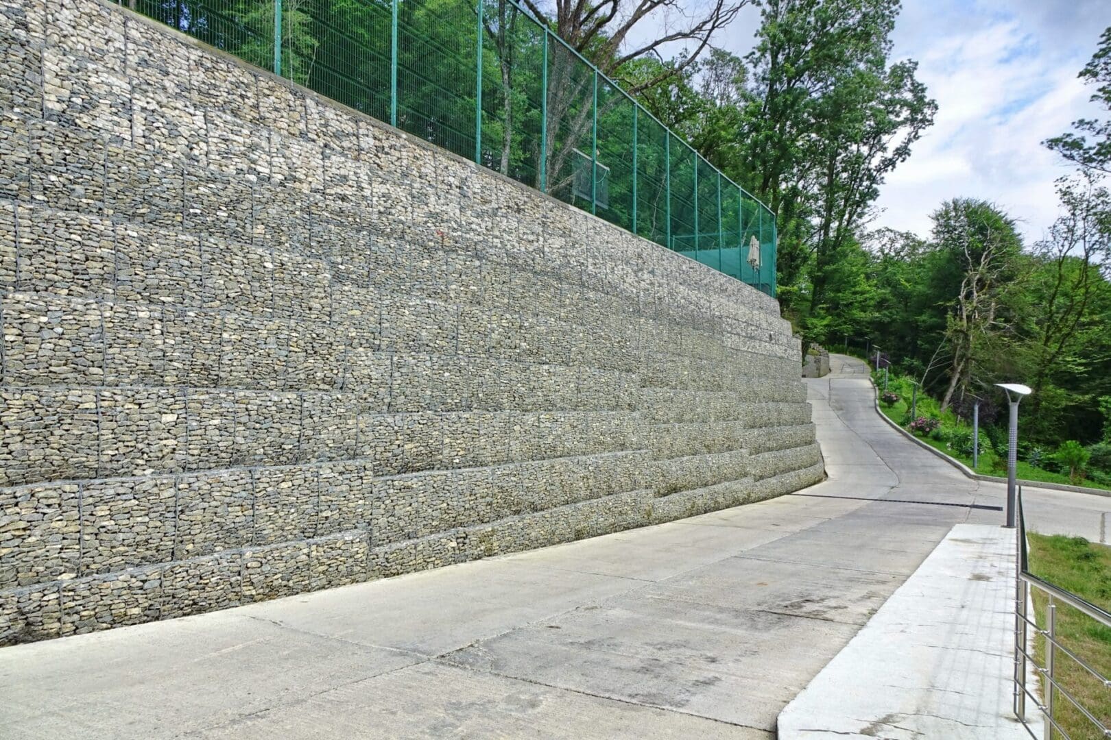 A stone wall with a green fence on the side.