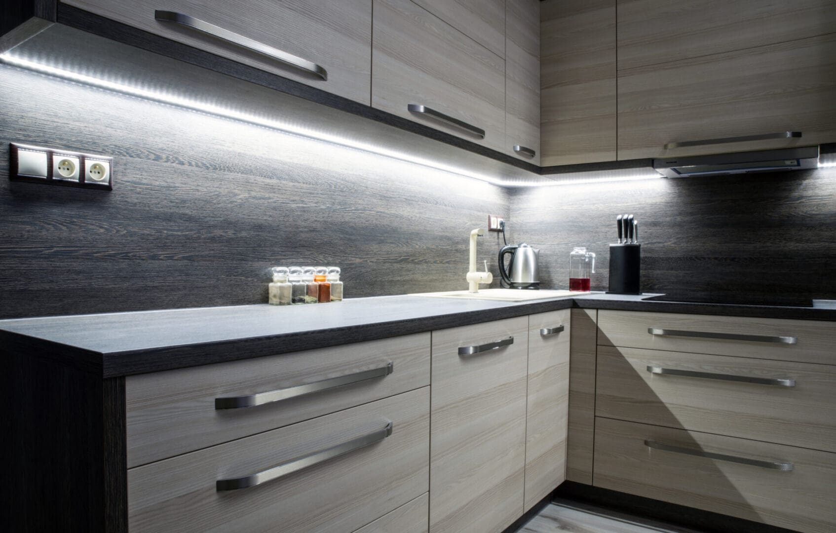 A kitchen with white cabinets and black counter tops.